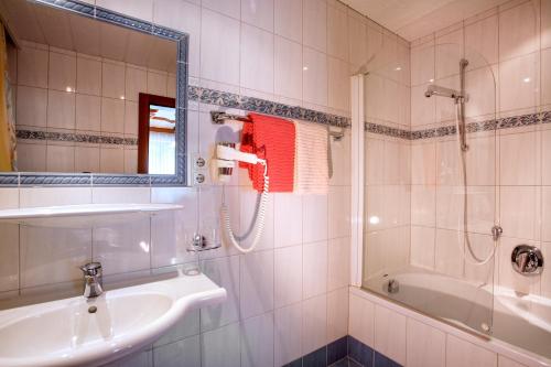 a bathroom with a sink and a shower and a tub at Pension Alpengruss in Gerlos