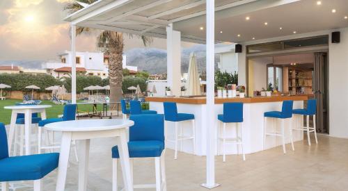 a restaurant with a bar with blue chairs and tables at Neon Hotel in Stalida