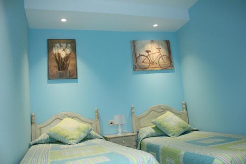 two beds in a room with blue walls at Casa Santiago in Comillas