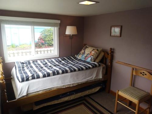 a bed in a room with a window and a chair at Historic 1920s Cabin in Long Beach