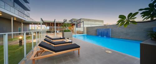 uma piscina com duas espreguiçadeiras ao lado de um edifício em The Sebel West Perth em Perth
