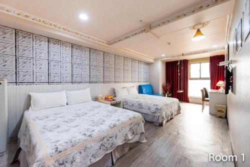 a hotel room with two beds and a table and chairs at Gwawa Hotel in Kaohsiung