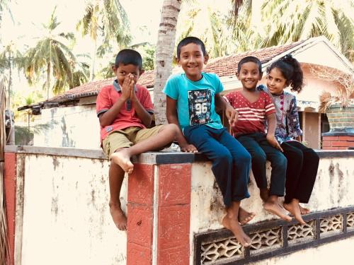 a group of children sitting on a wall at Wind Blend Kite Resort in Kalpitiya