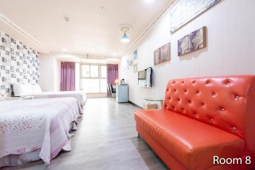 a hotel room with two beds and a red couch at Gwawa Hotel in Kaohsiung