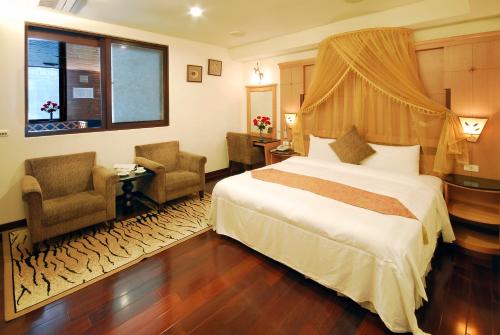 a hotel room with a bed and two chairs at Ming Lu Holiday Hotel in Renai