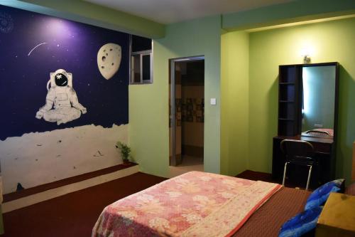 a bedroom with a bed and a wall with a astronaut mural at Yog Hostel- Rooftop Yoga & Backpacker Social Stay in Thamel, Kathamndu in Kathmandu