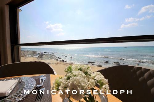 a table with a view of the beach from a window at Home Holiday Salento Monica's House Pescoluse in Marina di Pescoluse