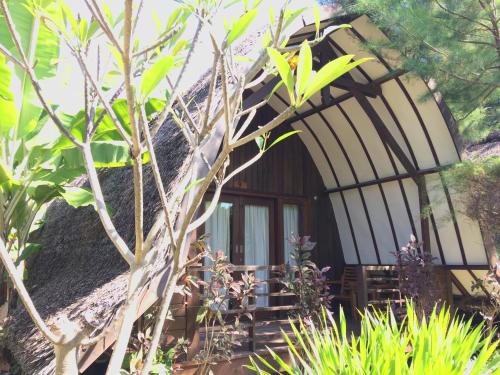 una casa con una ventana redonda y un árbol en Melati Cottage, en Gili Trawangan