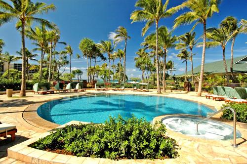 a swimming pool with palm trees and chairs in a resort at Ocean Villas at Turtle Bay in Kahuku