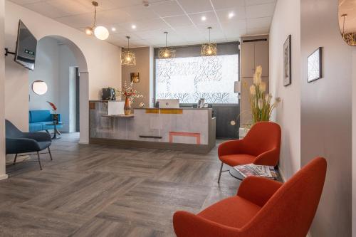 a lobby with orange chairs and a kitchen in the background at Hôtel Alcôve Nice in Nice