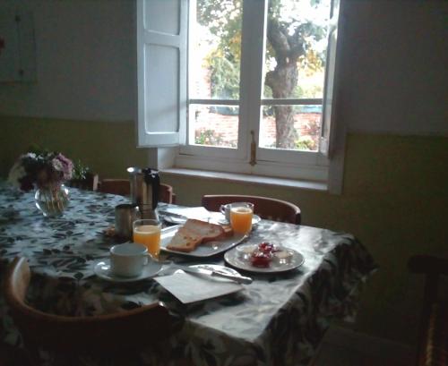a table with food and orange juice on it with a window at Albergue Peregrinos La Casa Verde in San Martín del Camino