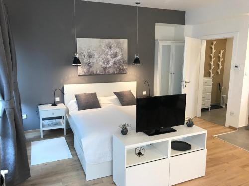 a bedroom with a white bed with a flat screen tv at Feels Like Home Apartments in Zagreb