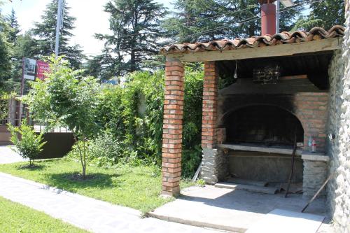 a brick oven in a yard with a tree at Hotel Kavkasioni in Kvareli