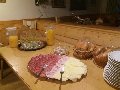 a table with a plate of cheese and meat and forks at Gasthaus Furlhütte in Vipiteno