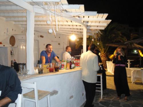 a group of people standing at a bar in a restaurant at Faros Resort in Azolimnos
