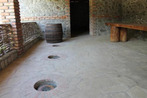 a patio with a barrel and a wooden bench at Hotel Kavkasioni in Kvareli