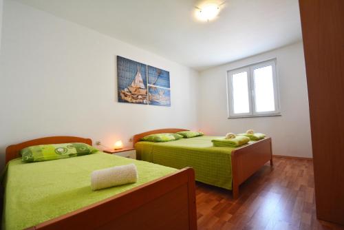 a bedroom with two beds with green sheets and a window at Apartments Barbati in Kustići