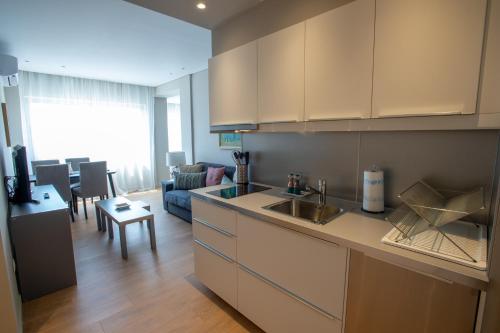 cocina con armarios blancos y sala de estar. en Athens Center Panoramic Flats, en Atenas