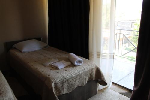 a bed with towels on it next to a window at Hotel Kavkasioni in Kvareli