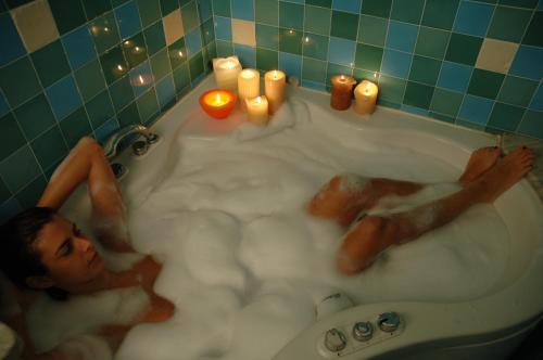 a man laying in a bath tub with candles at Hotel Giglio in Montecatini Terme