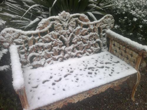 a bench covered in snow in a garden at Villa Della Certosa in Gambassi Terme