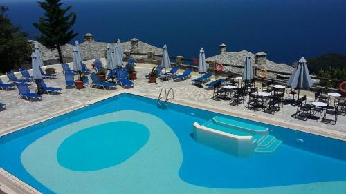 a large blue swimming pool with chairs and umbrellas at Pilio Sea Horizon Hotel in Tsagarada