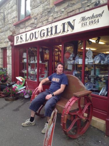 a man sitting on a bench in front of a store at Acara House B&B in Dublin