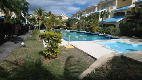 una piscina frente a un edificio con palmeras en Home Sweet Home, en Flic en Flac