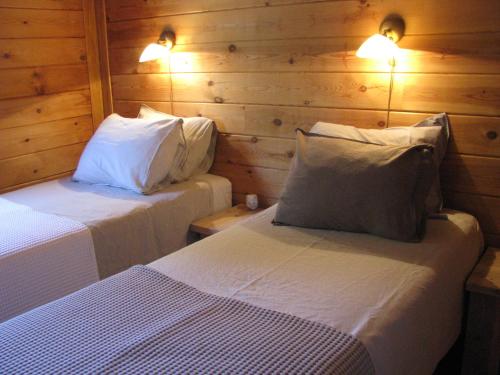 LliberにあるFinca Lliberのベッド2台 木製の壁と照明が備わる客室です。
