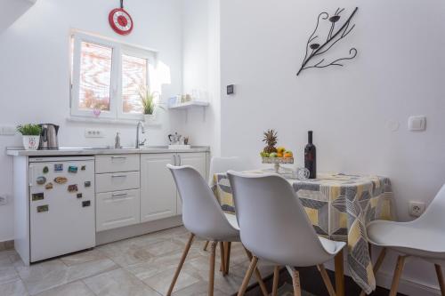 a kitchen with a table and white cabinets and a table and chairs at Studio Villa Ivka in Baška