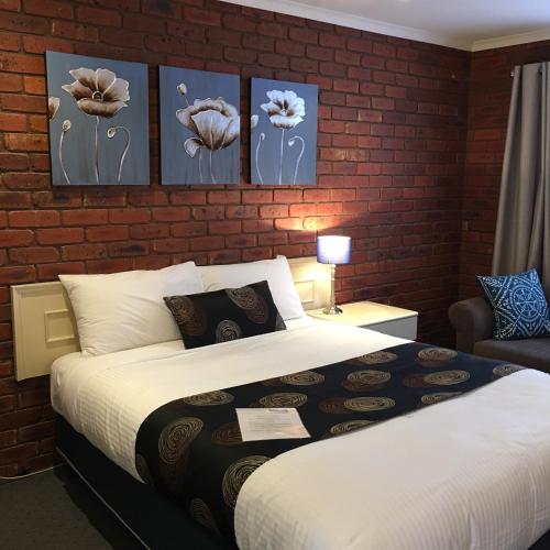 a bedroom with a bed and a brick wall at Melton Motor Inn and Apartments in Melton