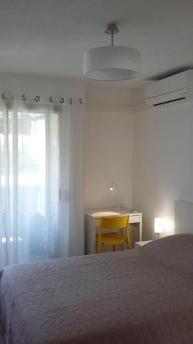 Un dormitorio con una cama y una silla amarilla. en Jardins du Pont du Lys, en Juan-les-Pins