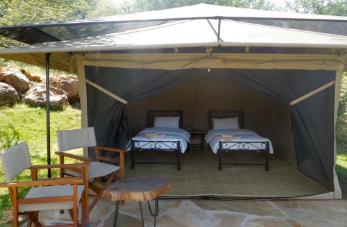 two beds in a tent with a table and chairs at Migombani Camp in Mto wa Mbu