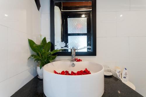 een badkamer met een witte wastafel met rode bloemen erin bij An Bang Stilt House Villa in Hội An
