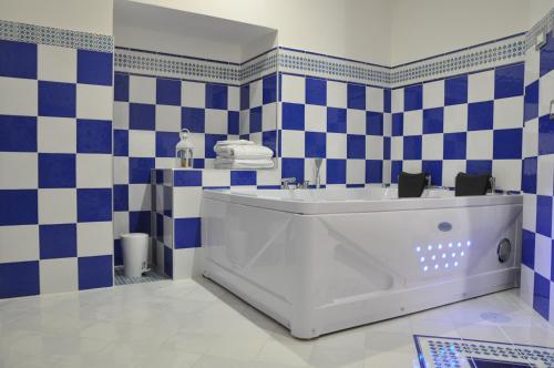 a bathroom with a tub and blue and white tiles at SALERNO COSTA D'AMALFI SUITE in Salerno