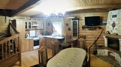 a kitchen with wooden walls and a table and a fireplace at Gostynniy Dvir in Forest Коттеджи in Migovo