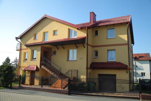 ヤストシェンビャ・グラにあるPokoje Goscinne Bartoszの黒柵の大黄色い家