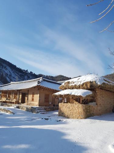 a building with snow on the ground in front of it at Jukheon Traditional House in Andong