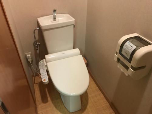 a white toilet in a bathroom with a toilet paper dispenser at Kotonoyado Musashino in Nara