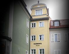 un bâtiment jaune avec une tour d'horloge à côté d'un bâtiment blanc dans l'établissement Elements Hotel, à Ratisbonne