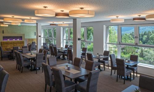 ein Esszimmer mit Tischen und Stühlen und Fenstern in der Unterkunft Arthur's Hotel und Apartments am Achensee in Maurach