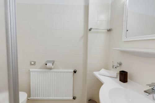 a white bathroom with a sink and a toilet at Hotel Himmelreich in Mariazell