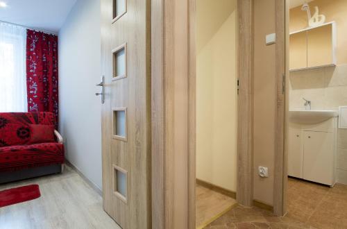 ザコパネにあるPrestige Apartament Jagiellonskaの赤いソファとシンク付きの部屋のドア