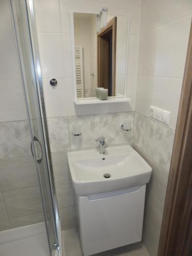 a white bathroom with a sink and a shower at Apartmán LEMON in Vysoke Tatry - Tatranska Lomnica.