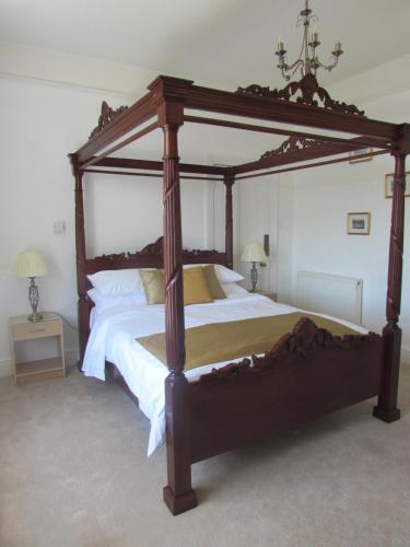 a large wooden canopy bed in a bedroom at Kenmuire Apartment in Weymouth