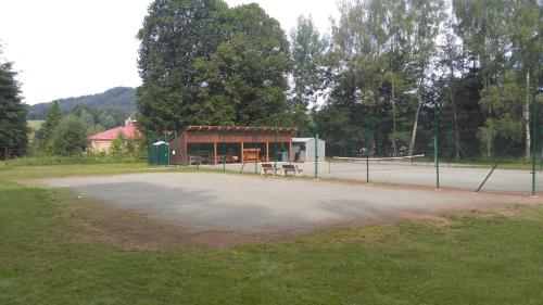 a tennis court with a bench in front of a building at Ubytování u Šveců u Adršpachu in Jívka