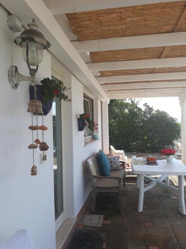 um alpendre com uma mesa branca, uma mesa e um pátio em Villa Clementina em Fondi