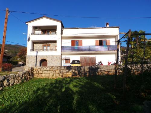una grande casa bianca con un muro di pietra di Apartments Miro a Ičići