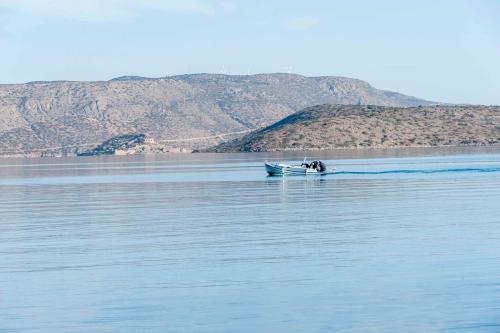 a boat on the water with mountains in the background at Elounda Akti Olous (Adults Only) in Elounda