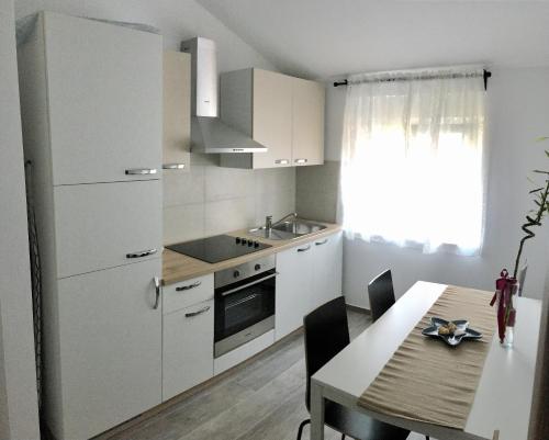 a kitchen with white cabinets and a table with a dining room at Fine & Shine in Pula